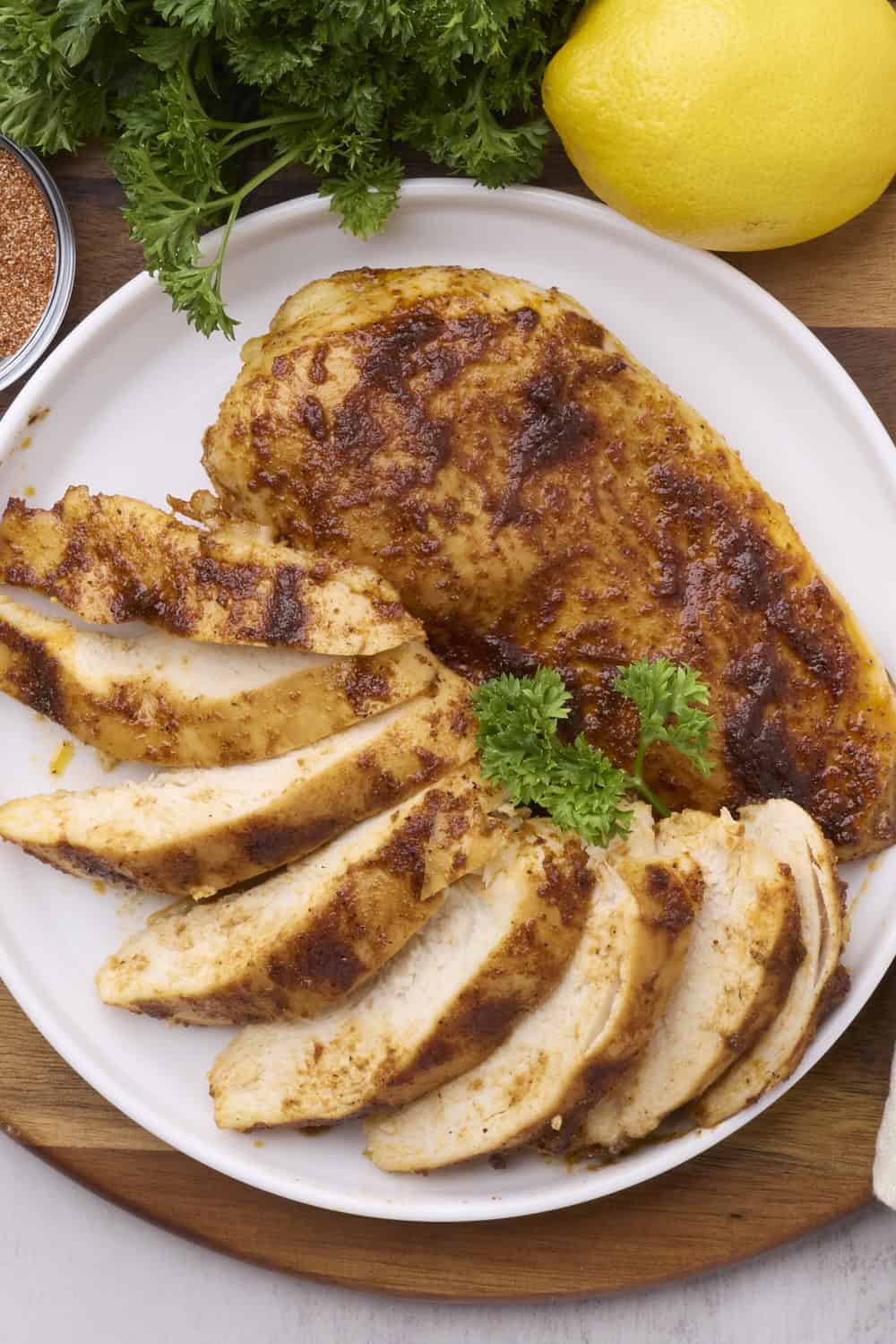 A white plate with one whole Cast Iron Skillet Chicken Breast and one sliced chicken breast fanned out.